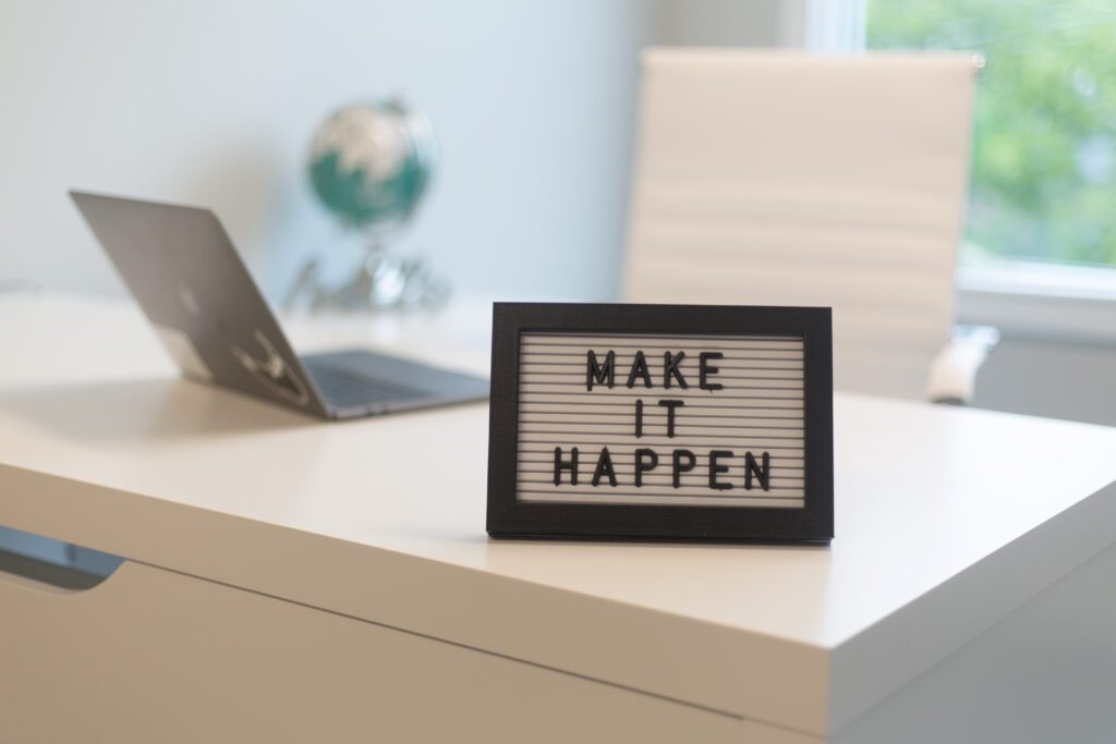 A picture frame in the office displays the text 'Make it happen.'
