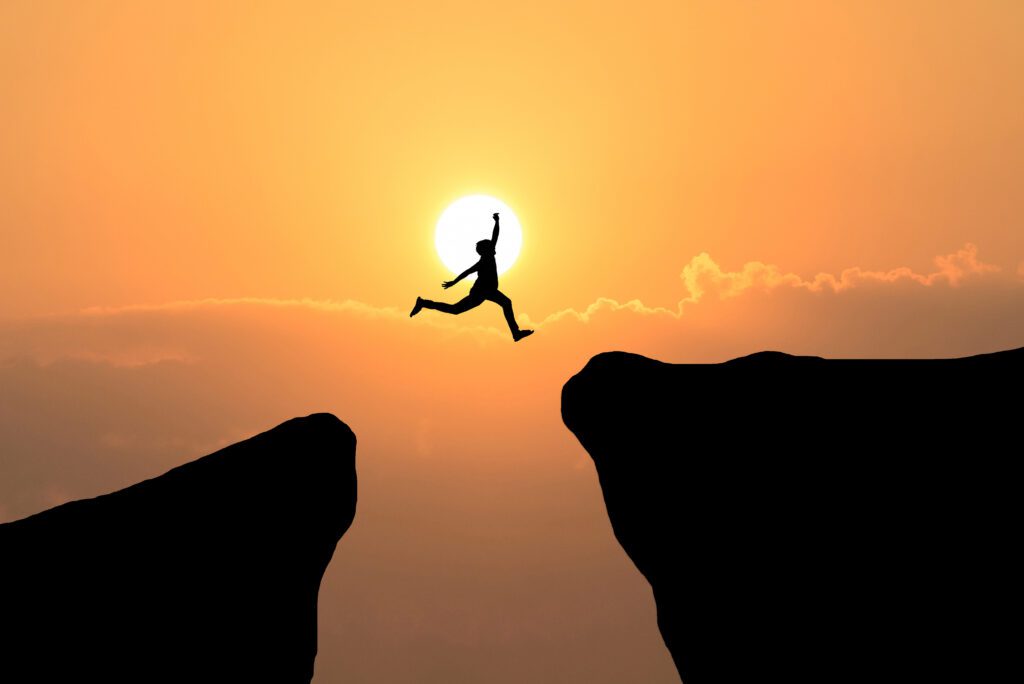 Courage man jump through the gap between hill just like taking massive action to achieve success.