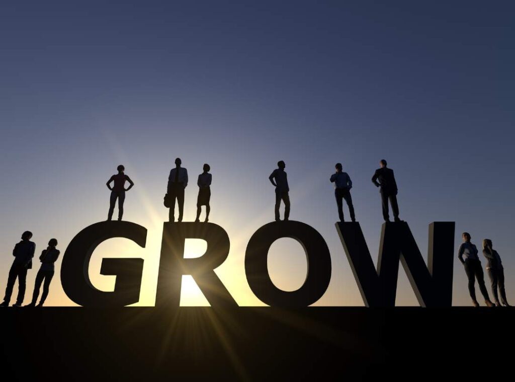 A group of people standing above the word "GROW".
